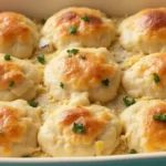 Homemade chicken and biscuit casserole with creamy chicken filling and golden buttermilk biscuits on a white plate.