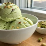 Close-up of homemade pistachio ice cream recipe with chopped nuts on top, showcasing creamy texture in a natural kitchen setting.