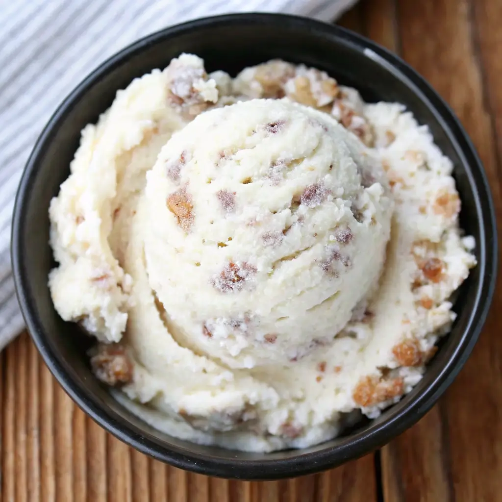 A scoop of homemade Grape Nut Ice Cream in a black bowl, showing creamy vanilla texture with crunchy grape nut cereal bits a classic Caribbean ice cream and nostalgic no egg ice cream recipe.