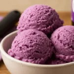 Tub of homemade Grapico Ice Cream on a messy kitchen counter with spoon and soda can