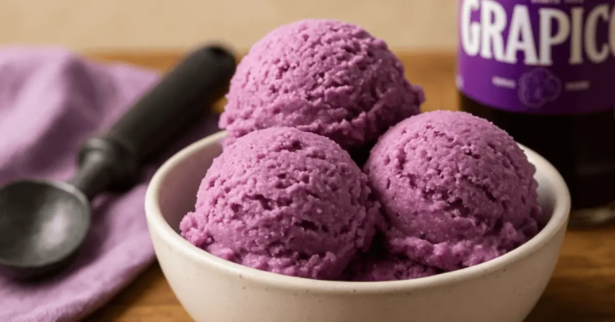 Tub of homemade Grapico Ice Cream on a messy kitchen counter with spoon and soda can