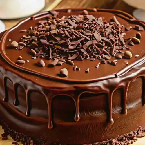 Rich chocolate cake with glossy homemade Costco-style chocolate icing and ganache topping, surrounded by ingredients like cocoa powder and chocolate bars.