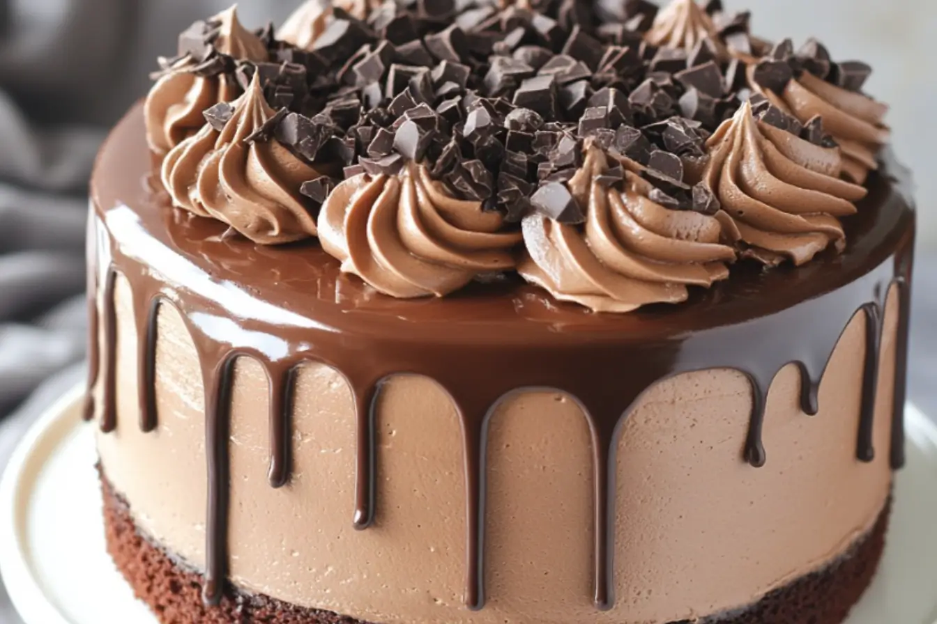 Triple chocolate fantasy cake with mousse layers, chocolate ganache drip, and decorative swirls topped with chocolate chunks.