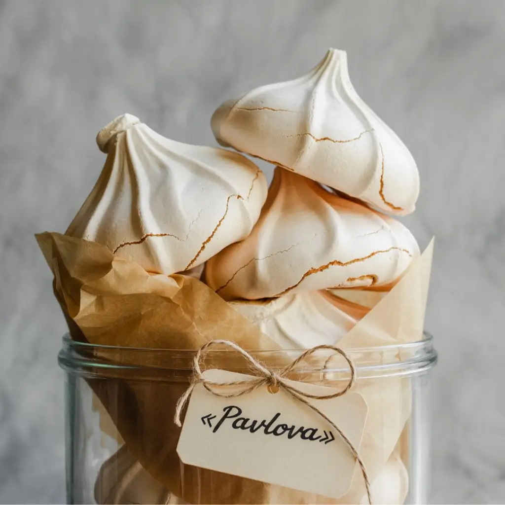 rose pavlova shells and overlay text explaining storage and make-ahead tips for pavlovas and whipped cream