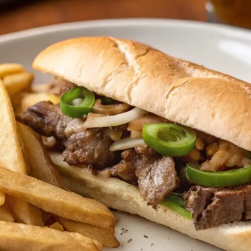 Authentic Philly Cheesesteak Recipe showing ribeye beef, sautéed onions, peppers, and melted provolone cheese in a toasted Amoroso roll.