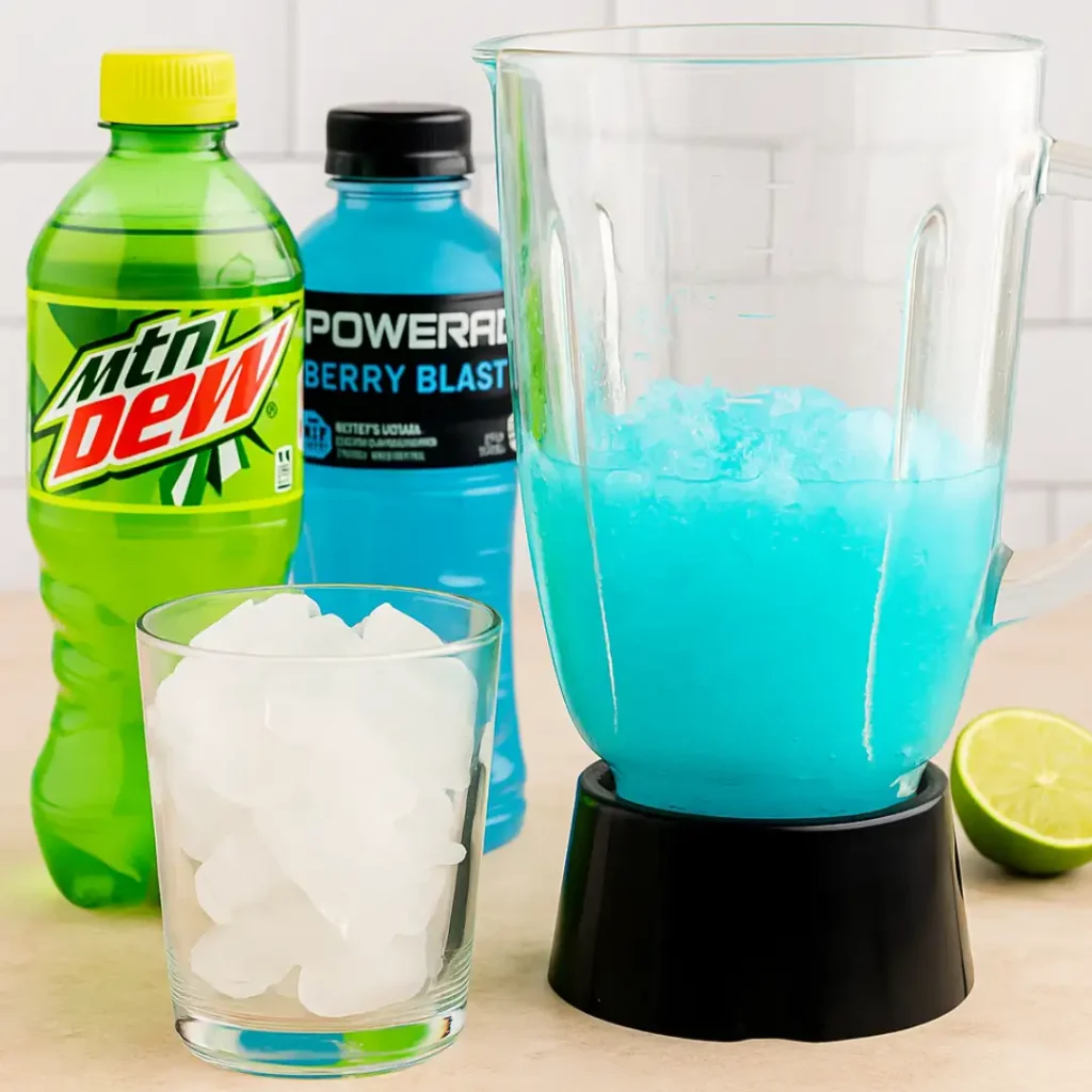 Blender with Baja Blast mixture, Mountain Dew, Powerade, ice, and lime on counter.