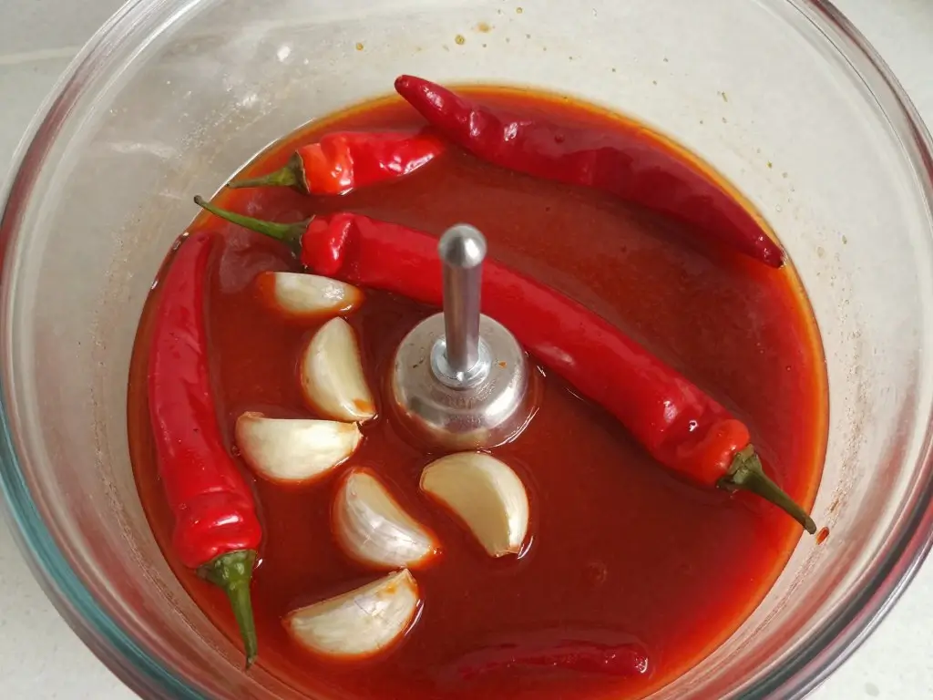 Red chile sauce for pozole recipe with fresh chiles and garlic in a blender bowl before mixing into the broth