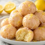 Glazed 4 ingredient lemon donuts with fresh lemon zest served on a white plate.
